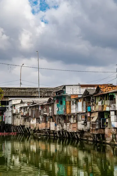 Nehir kenarındaki gecekondu evinin manzarası. Suyu kirlenmiş yeşil ve reklam odası için gökyüzü arkaplanı var. Nehrin kıyısındaki gecekondularda