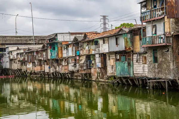 Nehir kenarındaki gecekondu evinin manzarası. Suyu kirlenmiş yeşil ve reklam odası için gökyüzü arkaplanı var. Nehrin kıyısındaki gecekondularda