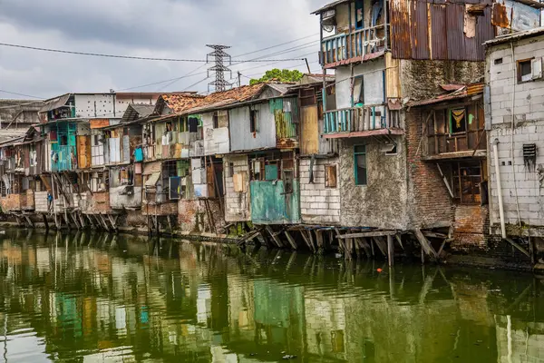 Nehir kenarındaki gecekondu evinin manzarası. Suyu kirlenmiş yeşil ve reklam odası için gökyüzü arkaplanı var. Nehrin kıyısındaki gecekondularda