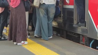 Platformda duran insanlar elektriğe girmek için kuyruğa giriyorlar. Trene binmek isteyen yolcular.