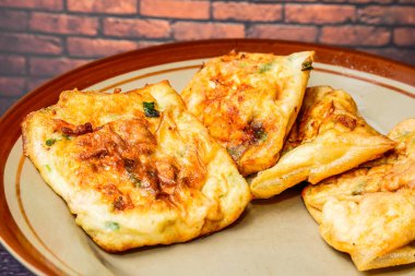 Boş reklamlar için kırmızı tuğla duvarlı bir tabakta Martabak yumurtaları.