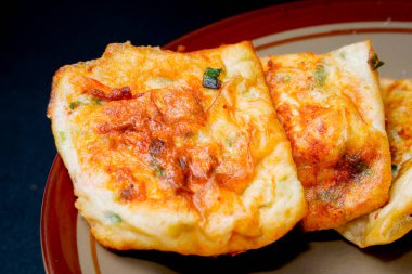 Reklam odası için izole edilmiş siyah bir tabakta yumurta martabak yakın görüntüsü.