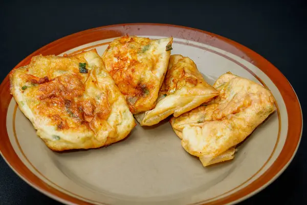 Reklam odası için izole edilmiş siyah bir tabakta yumurta martabak yakın görüntüsü.