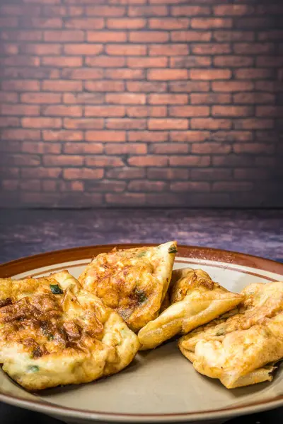 Boş reklamlar için kırmızı tuğla duvarlı bir tabakta Martabak yumurtaları.