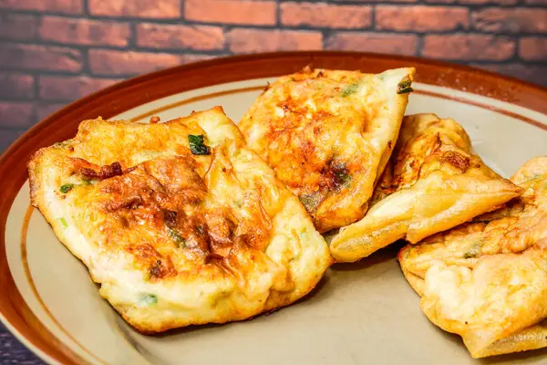 Boş reklamlar için kırmızı tuğla duvarlı bir tabakta Martabak yumurtaları.