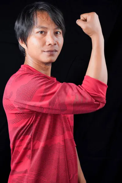 Kırmızı gömlekli Asyalı adamlar ellerini kaldırdı ve boş alanlar için siyah arka planlı el kaslarını göstermek için ellerini sıktılar..