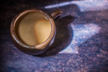 Güzel ışıklandırma arkaplanı ve reklam için boş yeri olan kilden bir fincanda kahve..