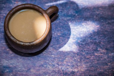 Güzel ışıklandırma arkaplanı ve reklam için boş yeri olan kilden bir fincanda kahve..