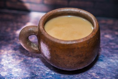 Güzel ışıklandırma arkaplanı ve reklam için boş yeri olan kilden bir fincanda kahve..