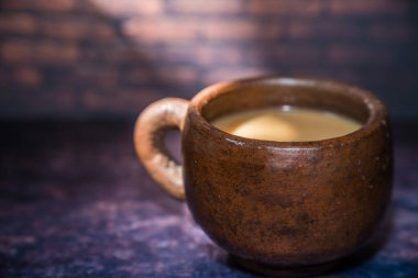 Güzel ışıklandırma arkaplanı ve reklam için boş yeri olan kilden bir fincanda kahve..