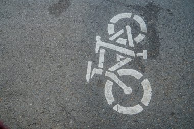 Asfalt zeminde bisiklet yolu tabelası, şehir yolunda beyaza boyanmış bisiklet tabelası, bisiklet kullanıcı şeridi tabelası.