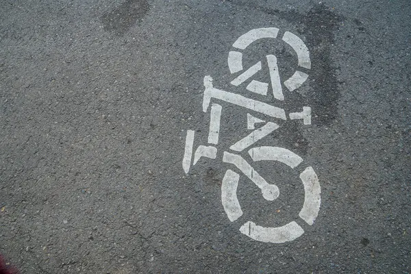 Asfalt zeminde bisiklet yolu tabelası, şehir yolunda beyaza boyanmış bisiklet tabelası, bisiklet kullanıcı şeridi tabelası.