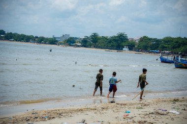 Jepara, Central Java, 30 Mart 2025, kıyıya demirlemiş balıkçı teknelerinin sesiyle sahil boyunca yürüyen çocuklar..