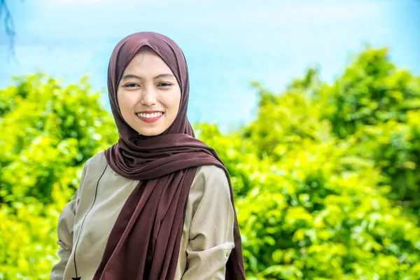 Güzel bir genç kadın, denizin kenarındaki manzaranın tadını çıkarırken gülümsedi, deniz kıyısının arka planına sahip dağın tepesinde gülümseyen güzel bir kadın..