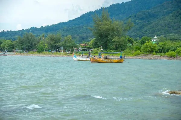 Denizin kıyısında bir dağ altyapısı olan balıkçı teknesi denizin kenarında dalgalar ve arka planda dağlar olan bir balıkçı teknesi..
