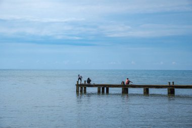 Jepara Merkez Java, 4 Nisan 2025, erkekler rıhtımda balık tutuyor. Balıkçılar sakin deniz suyunda iskelede balık tutuyorlar..