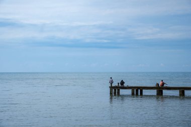 Jepara Merkez Java, 4 Nisan 2025, erkekler rıhtımda balık tutuyor. Balıkçılar sakin deniz suyunda iskelede balık tutuyorlar..