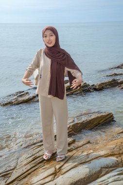 Müslüman Asyalı Kadınlar Deniz Taşı 'nın üzerinde duruyor. Reklam için boş bir alan var.