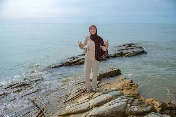 Müslüman Asyalı Kadınlar Deniz Taşı 'nın üzerinde duruyor. Reklam için boş bir alan var.