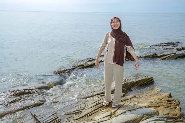 Müslüman Asyalı Kadınlar Deniz Taşı 'nın üzerinde duruyor. Reklam için boş bir alan var.