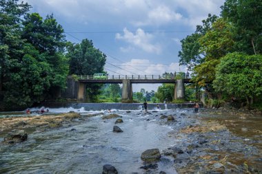 Jepara Central Java, 7 Nisan 2025, nehrin güzel manzarası nehirde oynayan insanlar ve köprüden geçen arabalar reklam alanı için gökyüzü arkaplanı..
