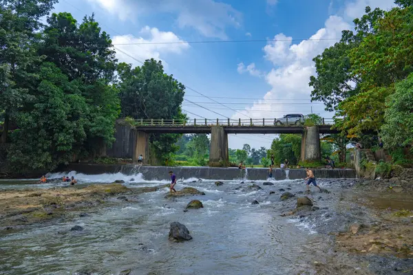 Jepara Central Java, 7 Nisan 2025, nehrin güzel manzarası nehirde oynayan insanlar ve köprüden geçen arabalar reklam alanı için gökyüzü arkaplanı..