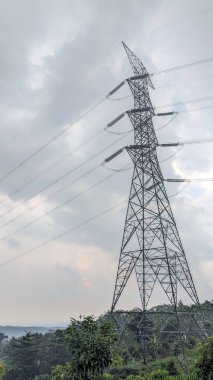 Parçalı bulutlu gökyüzünün altında yüksek elektrik geçiş kuleleri.