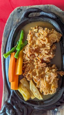 Kızarmış tavuk bifteği. Kahverengi sos, havuç ve yeşil fasulye karışımı.