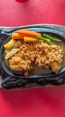 Kızarmış tavuk bifteği. Kahverengi sos, havuç ve yeşil fasulye karışımı.