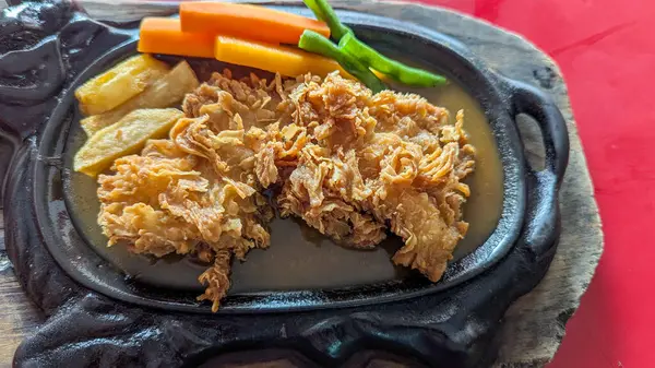 Kızarmış tavuk bifteği. Kahverengi sos, havuç ve yeşil fasulye karışımı.