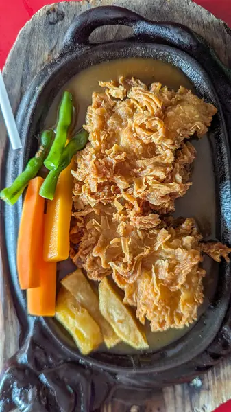 Kızarmış tavuk bifteği. Kahverengi sos, havuç ve yeşil fasulye karışımı.