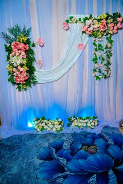 Dekorasyonun arka plan görüntüsü, çok güzel sentetik çiçeklerle süslenmiş kumaşlarla süslenmiş. Beyaz arka planda güzel bir düğün çiçeği buketi.