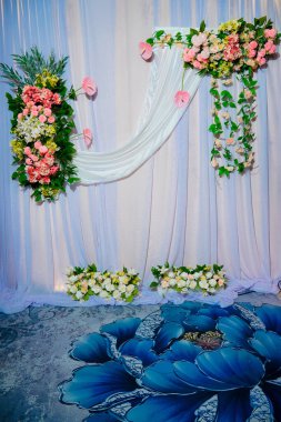 Dekorasyonun arka plan görüntüsü, çok güzel sentetik çiçeklerle süslenmiş kumaşlarla süslenmiş. Beyaz arka planda güzel bir düğün çiçeği buketi.
