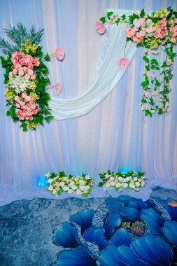 Dekorasyonun arka plan görüntüsü, çok güzel sentetik çiçeklerle süslenmiş kumaşlarla süslenmiş. Beyaz arka planda güzel bir düğün çiçeği buketi.