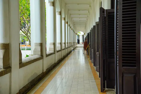 Sıralı kemerli sütunlar ve tahta kapılar olan uzun bir koridor..