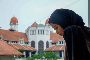 Peçeli Müslüman bir kadının görünüşü Lawang Sewu Semarang Müzesi 'nin arka planına bakıyor..