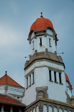 Kırmızı kubbe şeklinde çatısı olan yüksek bir bina reklam alanı için arka planda parlak mavi gökyüzü ile alçak bir açıdan görünüyor..