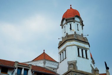 Kırmızı kubbe şeklinde çatısı olan yüksek bir bina reklam alanı için arka planda parlak mavi gökyüzü ile alçak bir açıdan görünüyor..