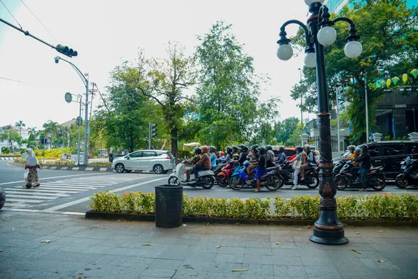 Semarang, Central Java, 1 Mayıs 2025, trafik ışıklarıyla kavşakta duran motosikletliler ve arabalar yayaların geçmesini bekliyor.