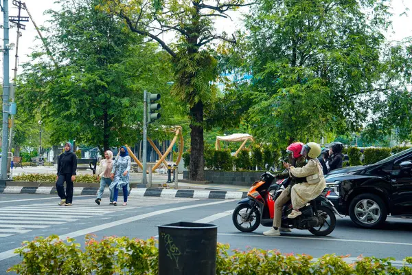 Semarang, Central Java, 1 Mayıs 2025, trafik ışıklarıyla kavşakta duran motosikletliler ve arabalar yayaların geçmesini bekliyor.