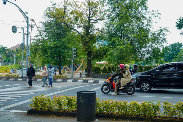 Semarang, Central Java, 1 Mayıs 2025, trafik ışıklarıyla kavşakta duran motosikletliler ve arabalar yayaların geçmesini bekliyor.