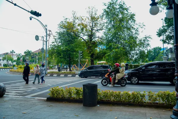 Semarang, Central Java, 1 Mayıs 2025, trafik ışıklarıyla kavşakta duran motosikletliler ve arabalar yayaların geçmesini bekliyor.