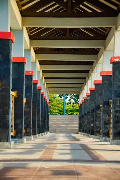 Çatıyı destekleyen sütunların olduğu uzun bir köprünün manzarası yol boyunca gölge desenli bir koridor oluşturuyor..