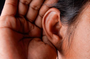 Kulak memesinin arkasına yerleştirilmiş bir adamın elini, reklam alanı için siyah bir arkaplana karşı dikkatle dinlemek üzere kapatın..