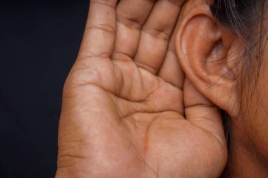 Kulak memesinin arkasına yerleştirilmiş bir adamın elini, reklam alanı için siyah bir arkaplana karşı dikkatle dinlemek üzere kapatın..