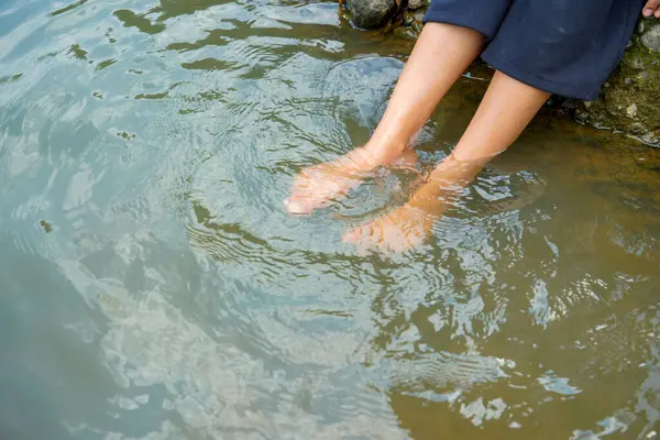 Nehir suyunda bir çift kadın ayağı sırılsıklam olmuş. Etrafı neşe dolu, ayakları nehir suyuna bulanmış..