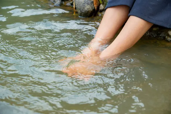 Nehir suyunda bir çift kadın ayağı sırılsıklam olmuş. Etrafı neşe dolu, ayakları nehir suyuna bulanmış..