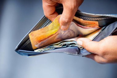 Adamın eli cüzdanını açtı ve diğer banknotların yanında beş bin rupi tuttu..