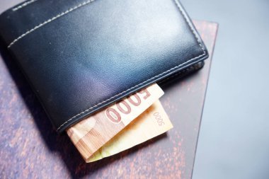 Beyaz dikişli siyah deri cüzdanın temiz görüntüsü reklam alanı için koyu bir zemin üzerinde rupiah banknotları olan siyah cüzdan dışarı fırlamış rupiah banknotlar.