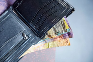 Beyaz dikişli siyah deri cüzdanın temiz görüntüsü reklam alanı için koyu bir zemin üzerinde rupiah banknotları olan siyah cüzdan dışarı fırlamış rupiah banknotlar.